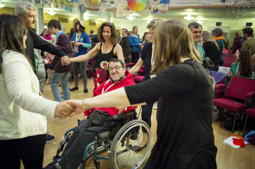 image of people dancing in a circle with a man in a wheelchair in the middle